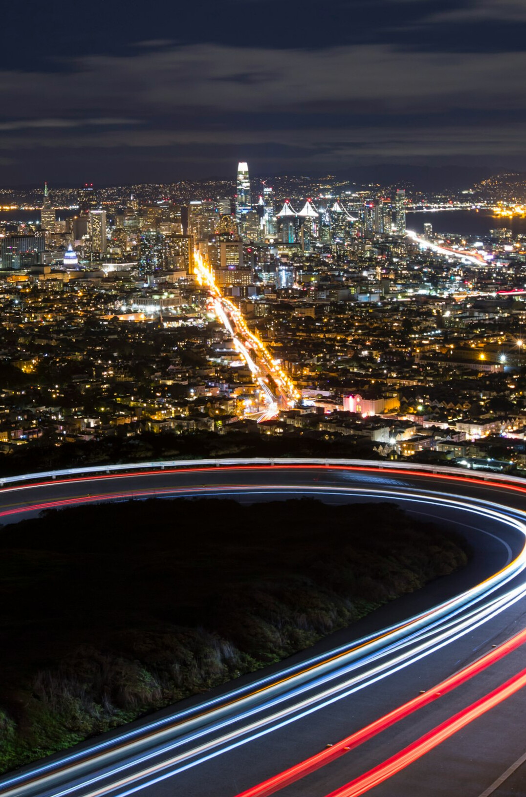 City skyline illuminated at night with traffic light trails