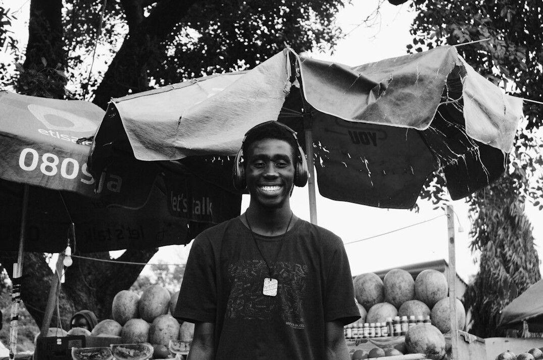 Portrait of a market vendor standing behind a stall of fruit and vegetables