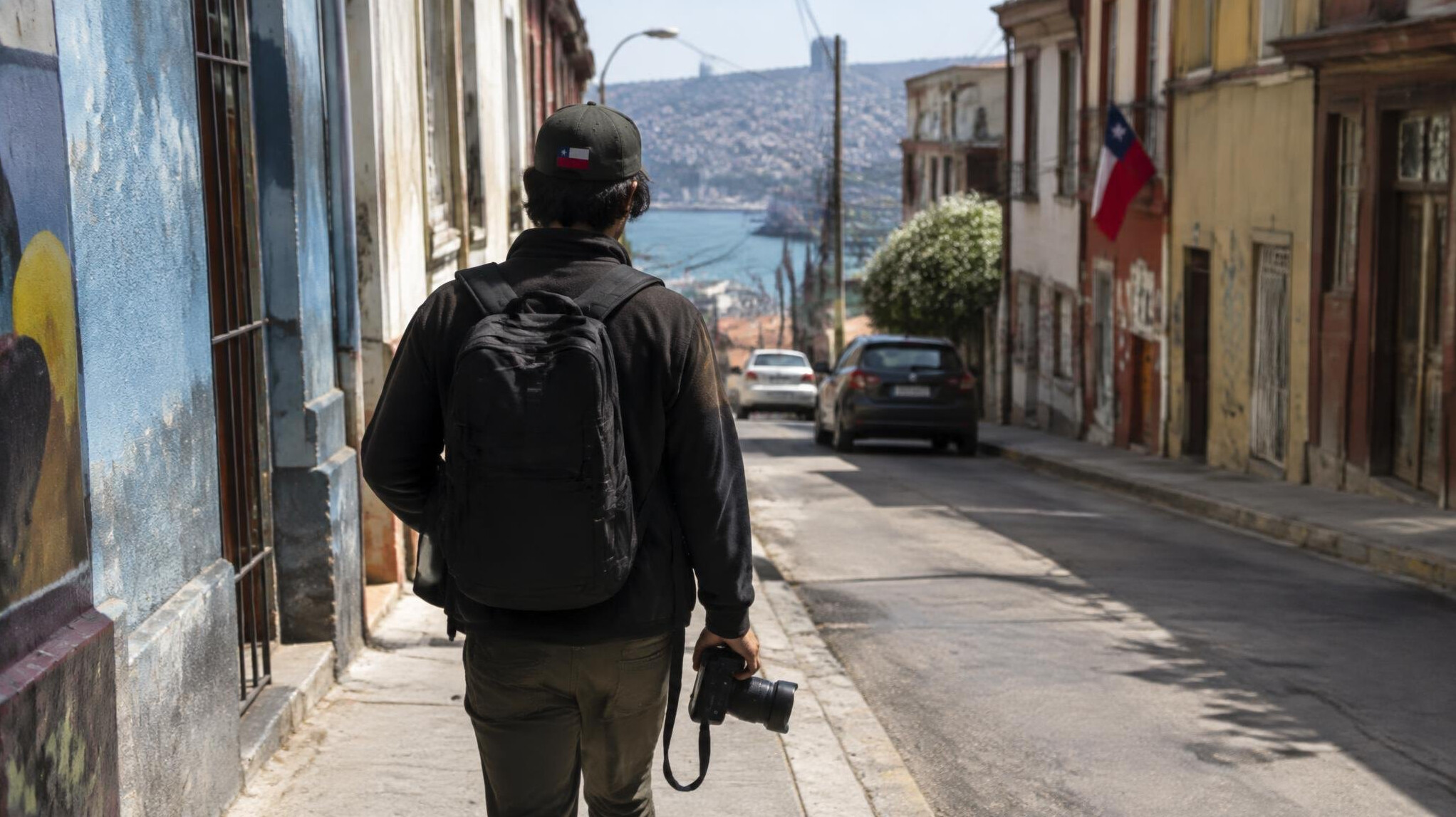 Photographer walking down a city street holding a camera