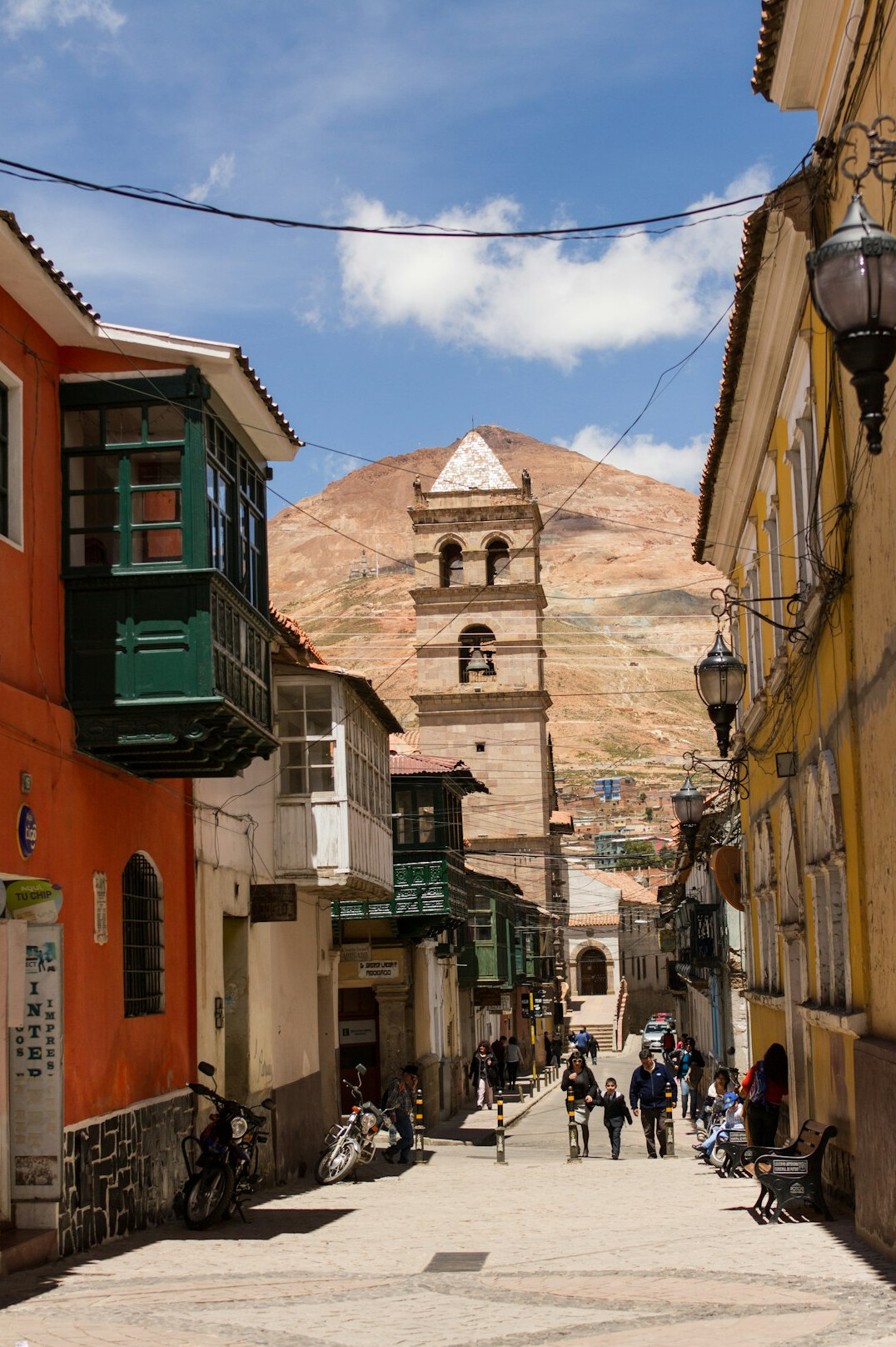 Wide street scene in a Latin American city at golden hour with pedestrians crossing